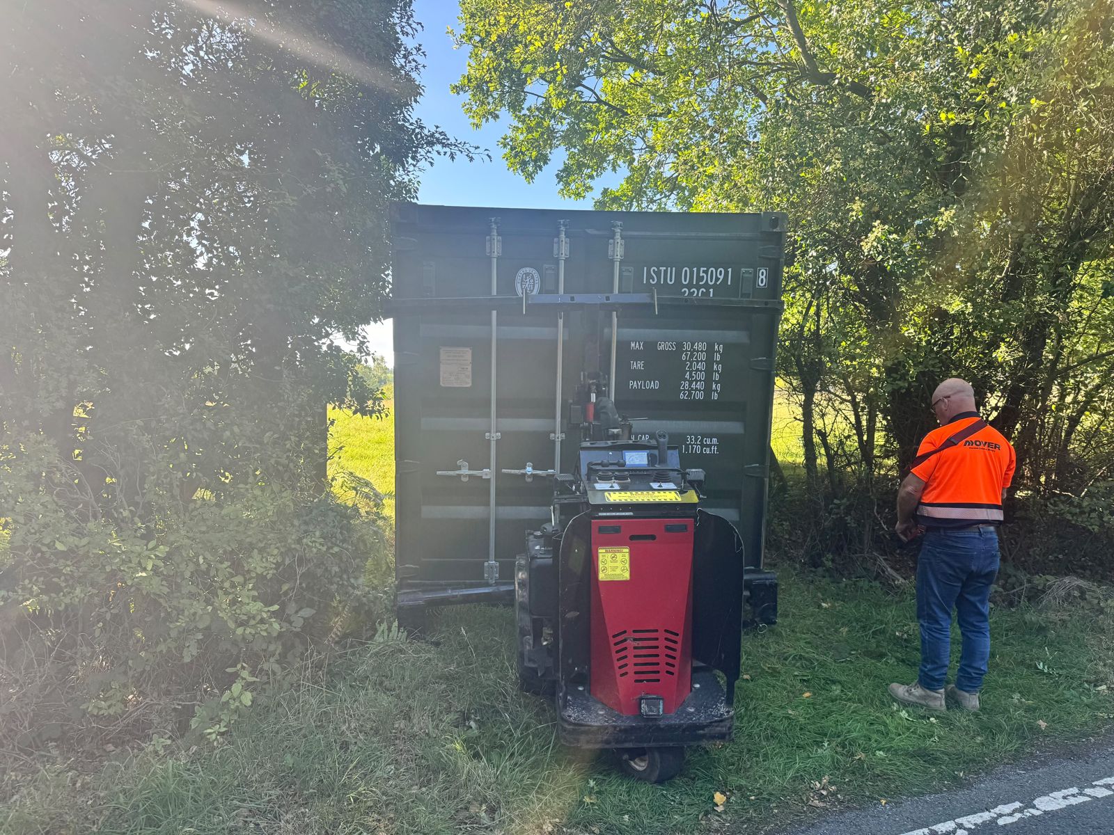 Green shipping container beside vegetation