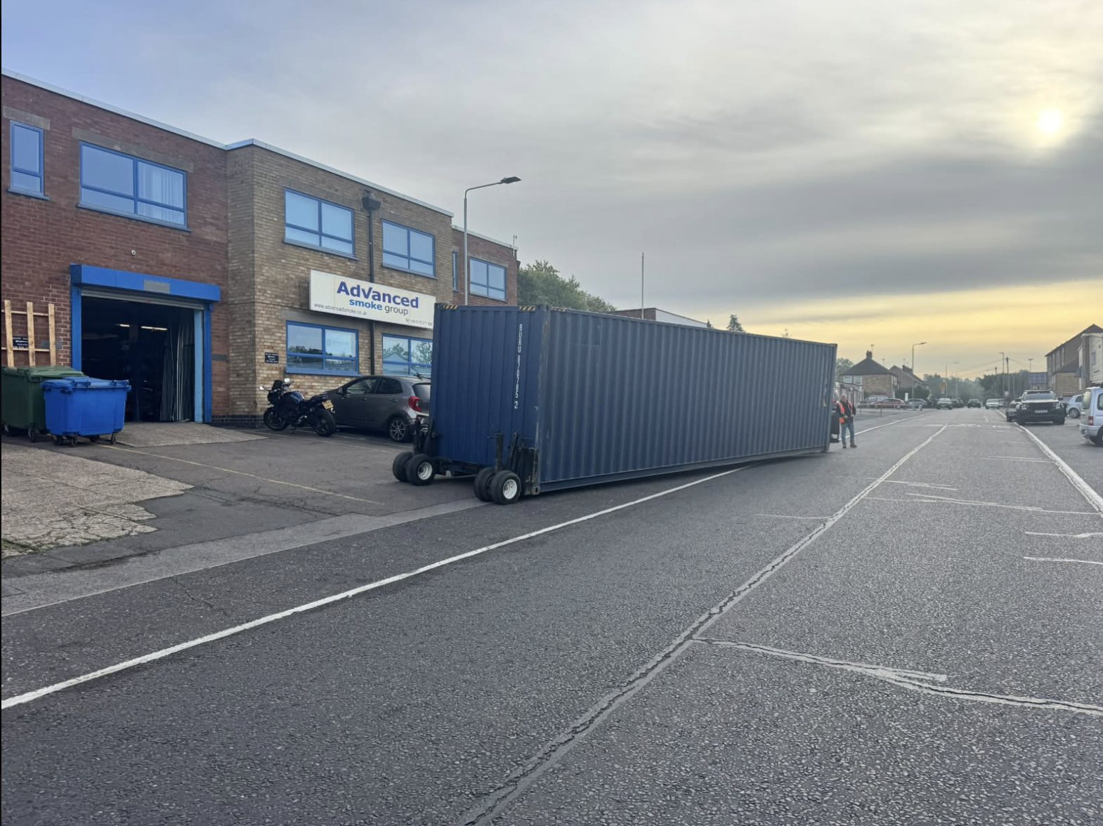 Shipping container on wheeled moving equipment outside a commercial building