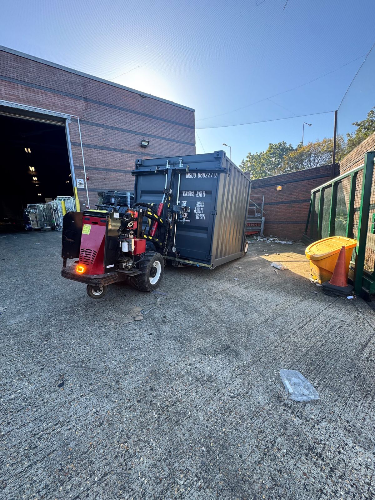 Shipping container outside the open entrance of a workshop building