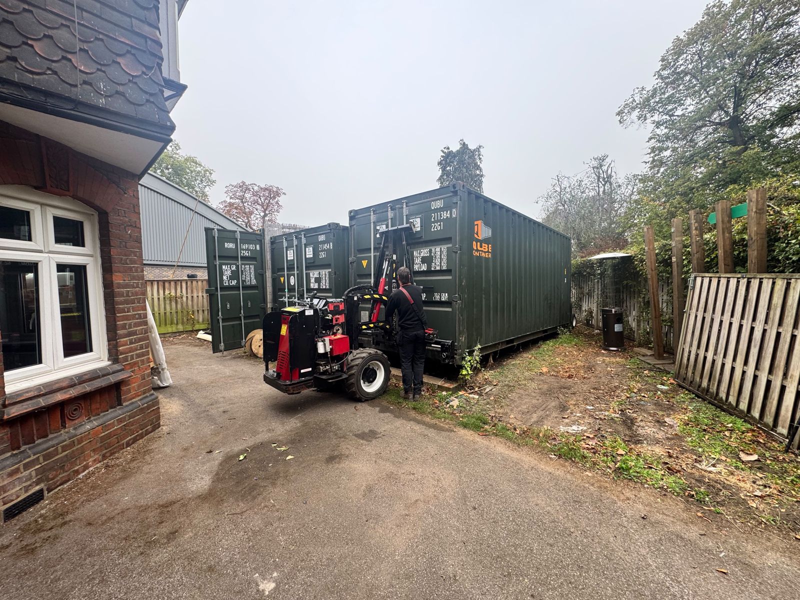 Shipping container next to a house and a wooden fence