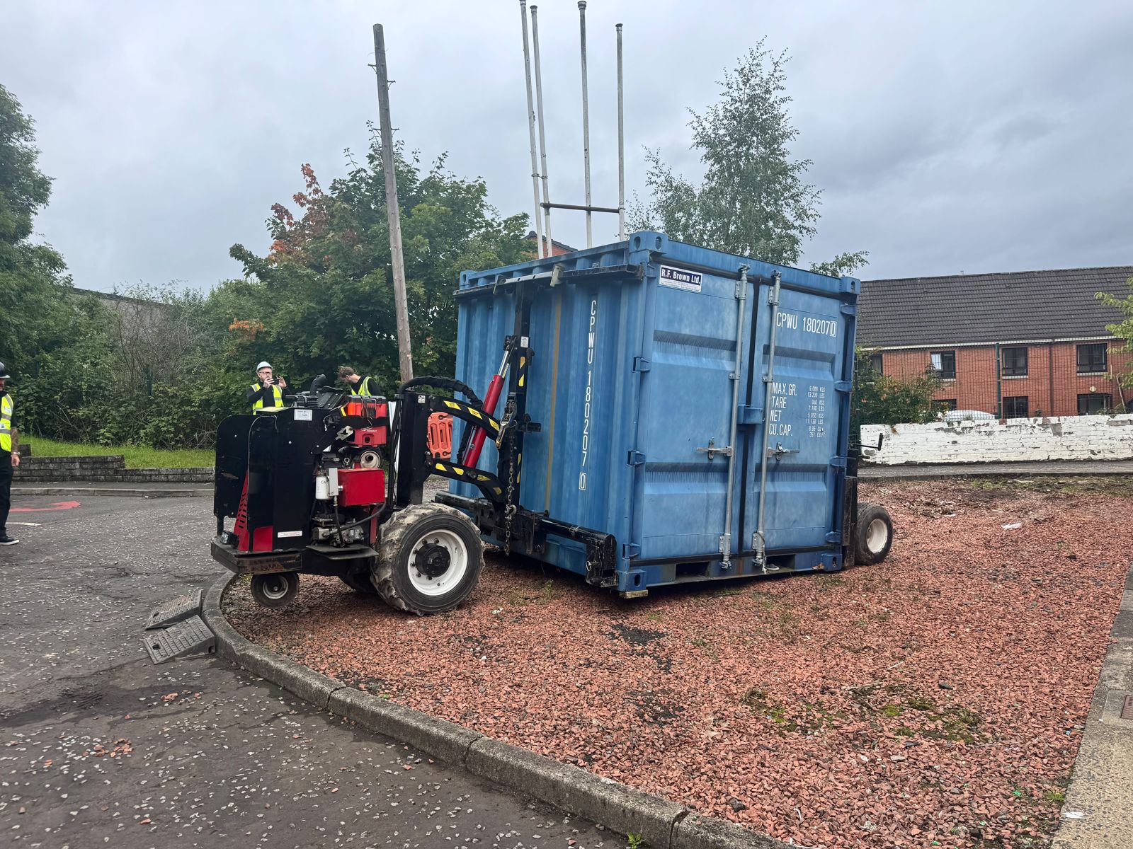 Blue shipping container beside a kerb and gravel surface